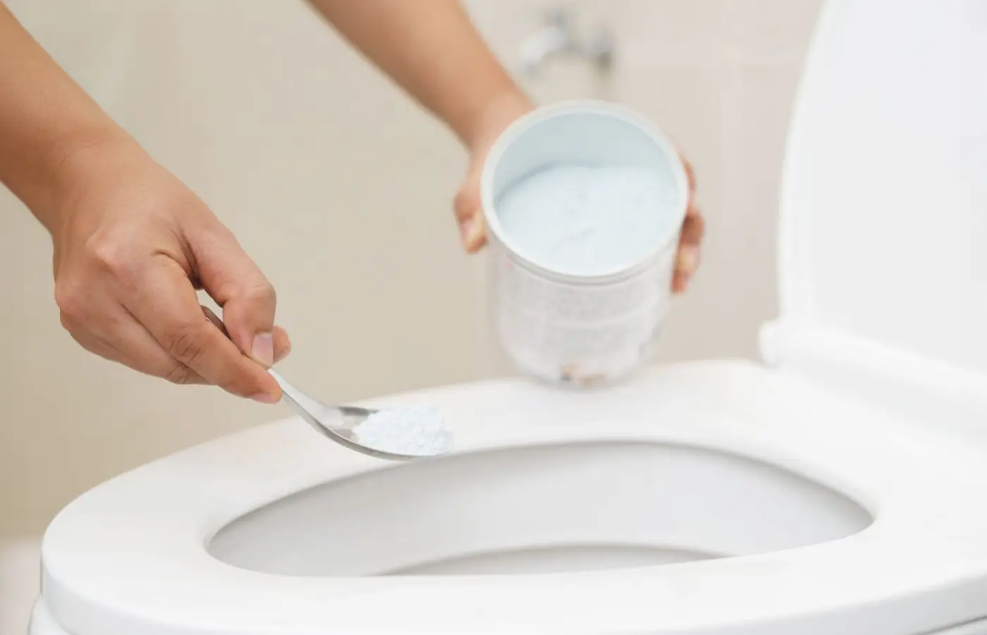 Personne versant de la poudre de nettoyage naturelle dans une cuvette de toilettes, illustrant une méthode écologique d’entretien des sanitaires.